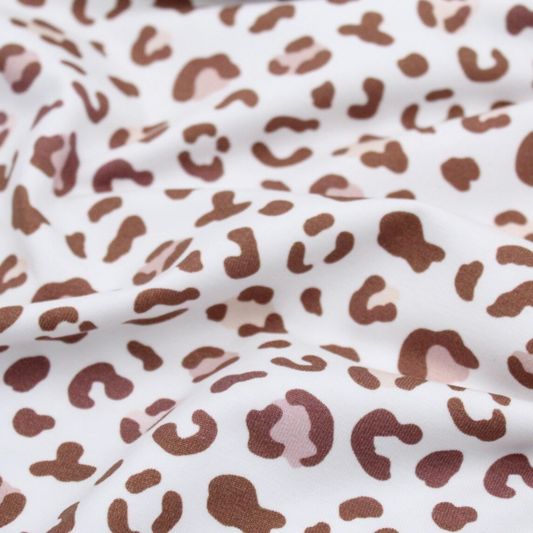 Weicher Jersey-Stoff mit stilvollem Leopardenmuster in Braun auf Weiß – ideal für Kleidung und Accessoires.