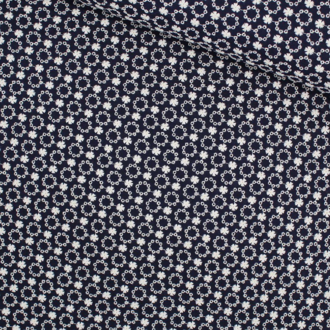 Breite Ansicht des Baumwollstoffs in Marineblau, der die Schönheit der weißen Blumenstickerei zeigt, ideal für romantische Nähprojekte.
