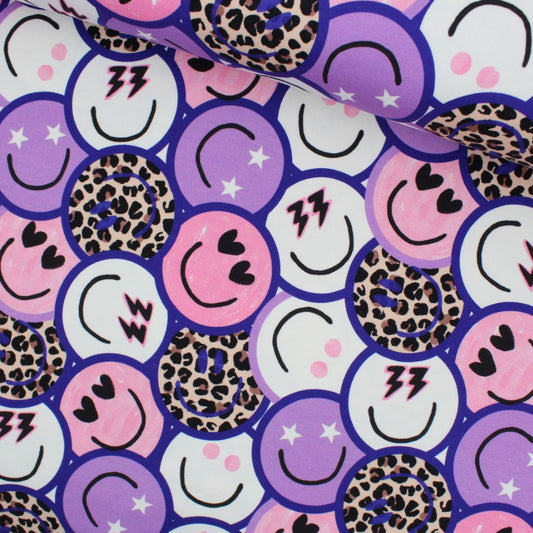 French Terry Stoff mit bunten Emoticons – Smileys, Herzen, Blitze und Leo-Print auf lila-pinkem Hintergrund.