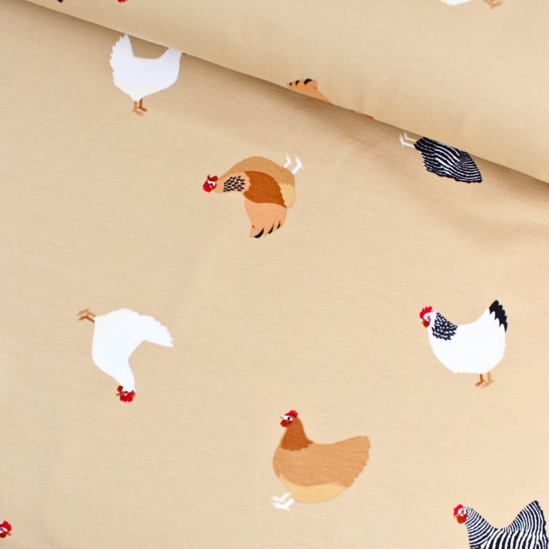French Terry Stoff mit bunten Hühnern auf beige – Nahaufnahme
