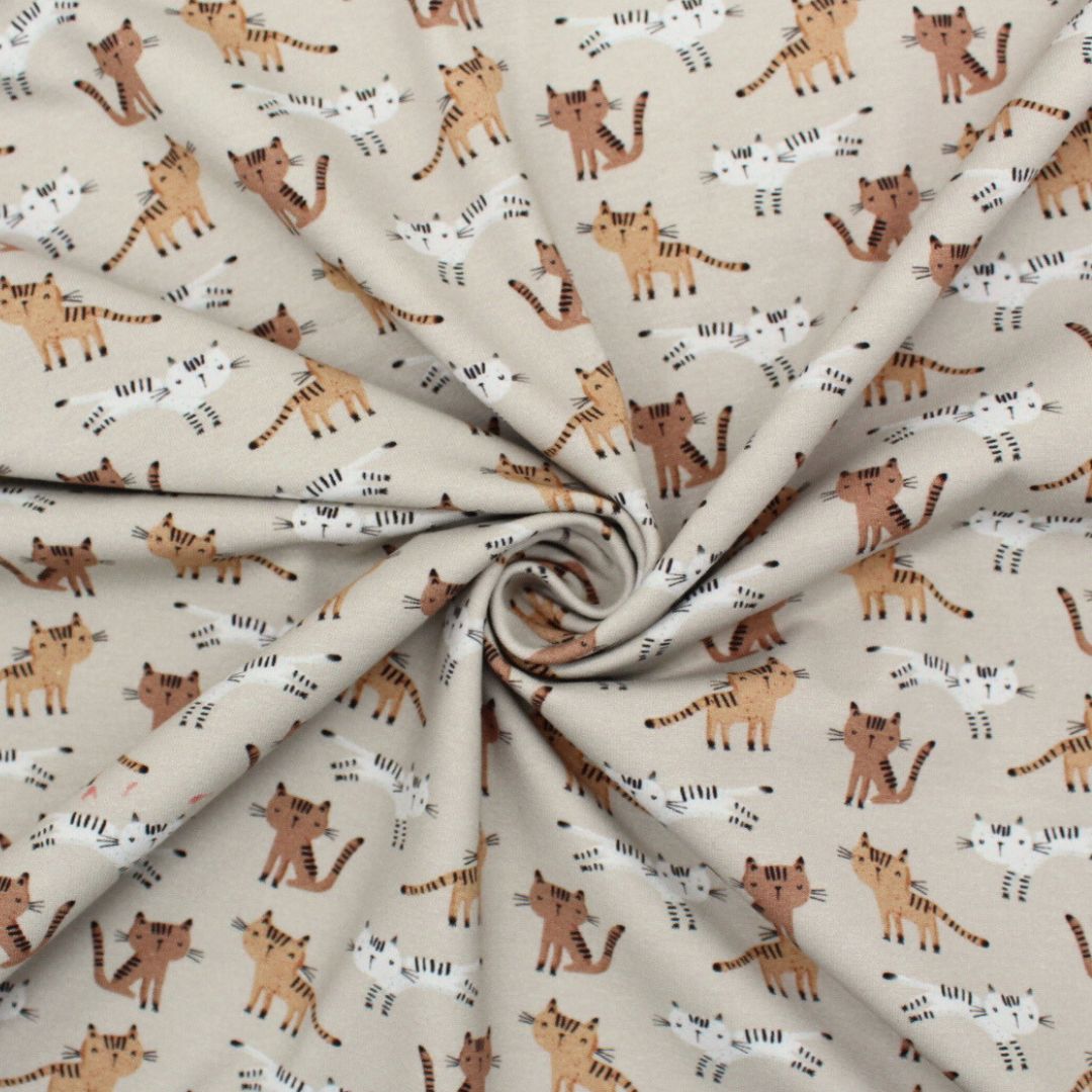 Detailansicht des weichen, elastischen Jersey-Stoffs mit Katzenmotiven auf beige, OEKO-TEX zertifiziert.