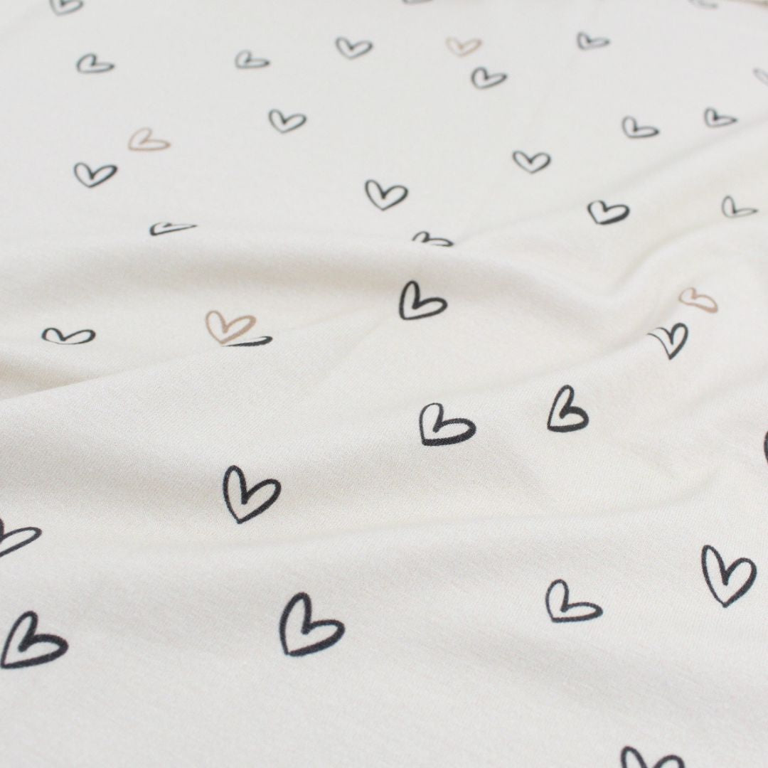 Detailaufnahme Jersey Stoff Kleine Herzen Sandgrau, weicher Baumwolljersey mit Elasthan