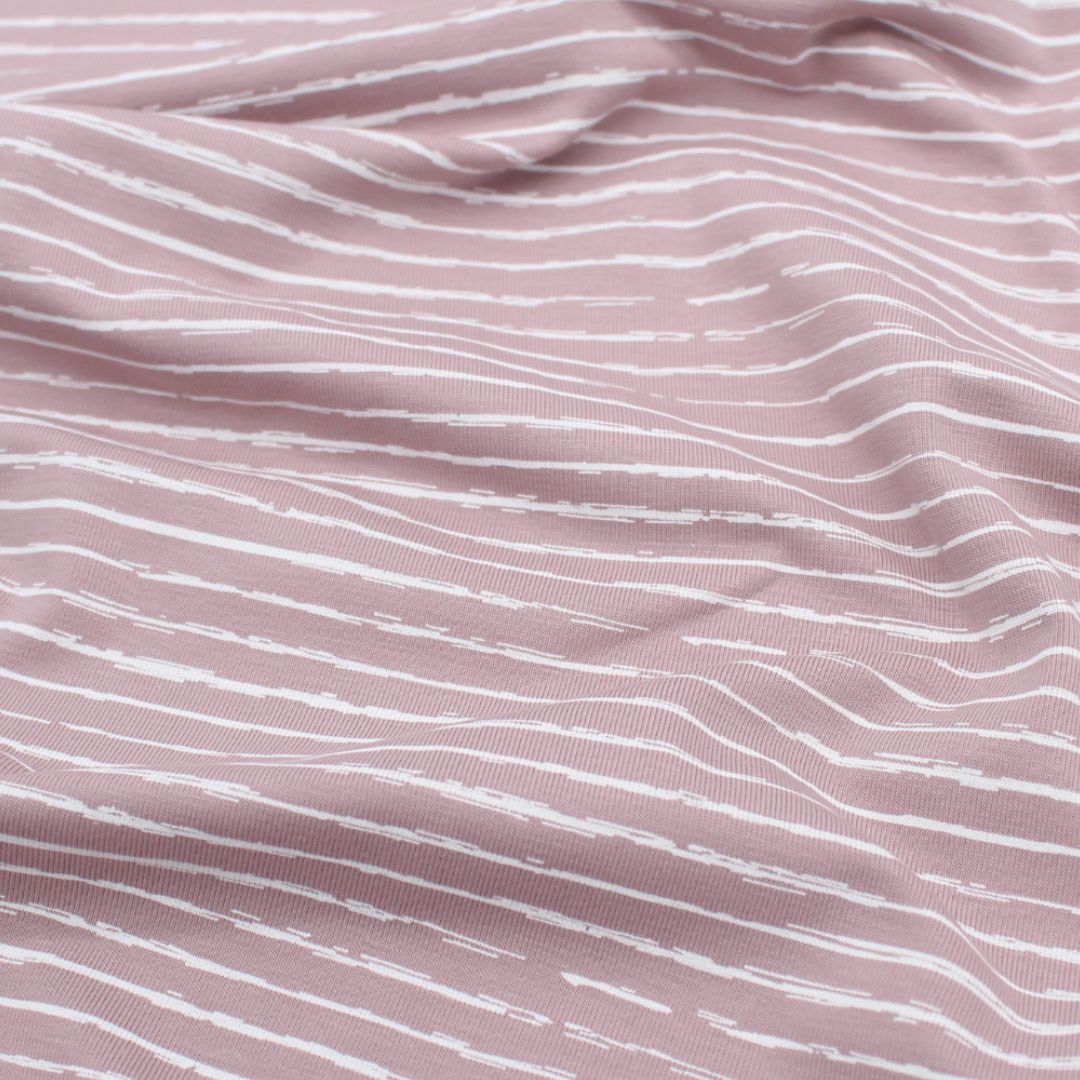 Jersey-Stoff mit weißen unregelmäßigen Streifen, ideal für Kleidung und modische Nähprojekte | Rosa