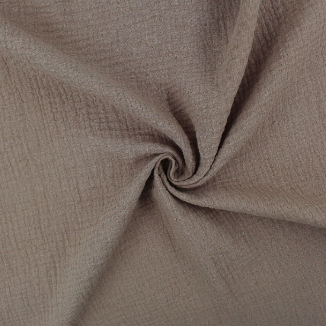 Weicher Musselinstoff (Double Gauze) in Taupe, locker drapiert, mit natürlicher Crinkle-Struktur und sanftem Fall.