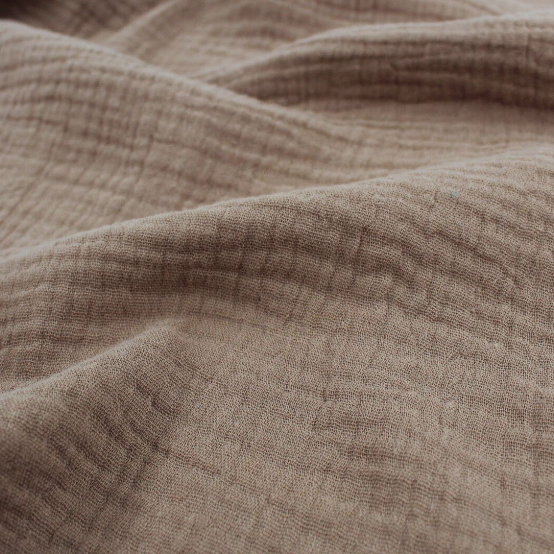 Mehrere Lagen Musselinstoff (Double Gauze) in Taupe übereinandergelegt, um die dezente Struktur und den sanften Farbton zu zeigen.