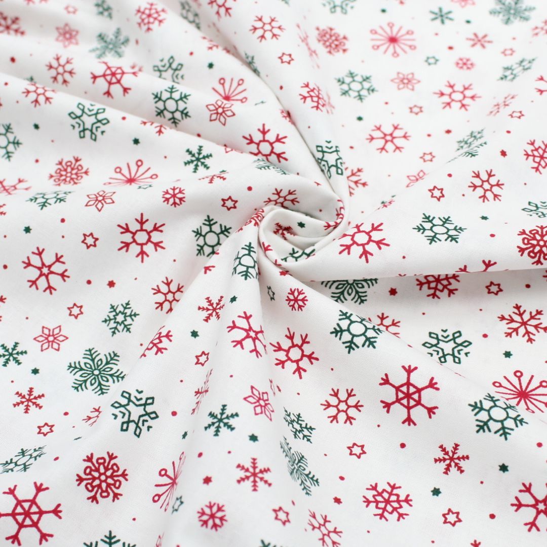 Popeline Weihnachtsstoff mit weißen Schneeflocken und goldenen Sternen auf einem harmonischen Hintergrund, perfekt für festliche Nähprojekte.
