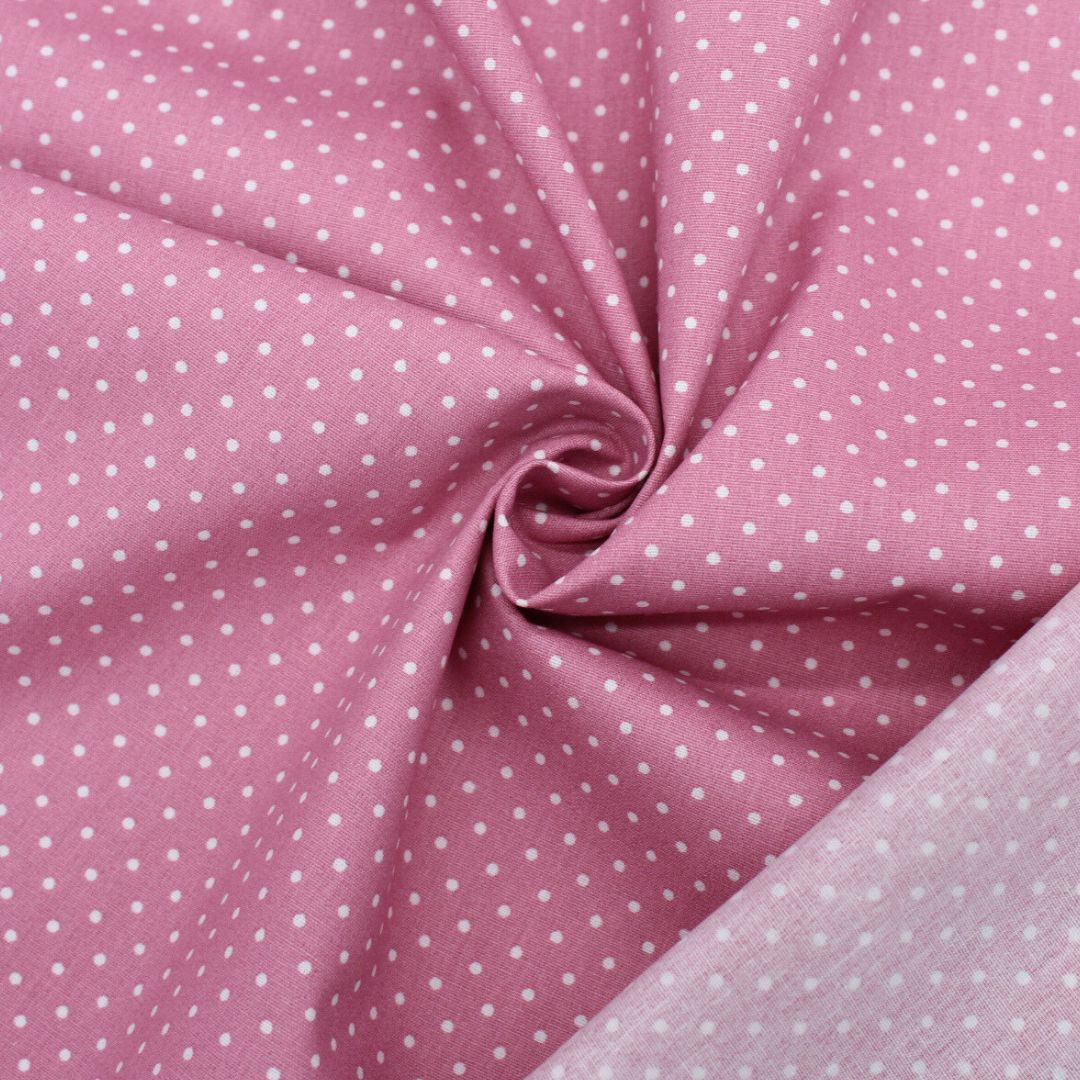 Popeline mit kleinen weißen Tupfen auf Rosa, ideal für die Herstellung von Sommerkleidern, Röcken und Kissenbezügen. Nahaufnahme mit Rückseite