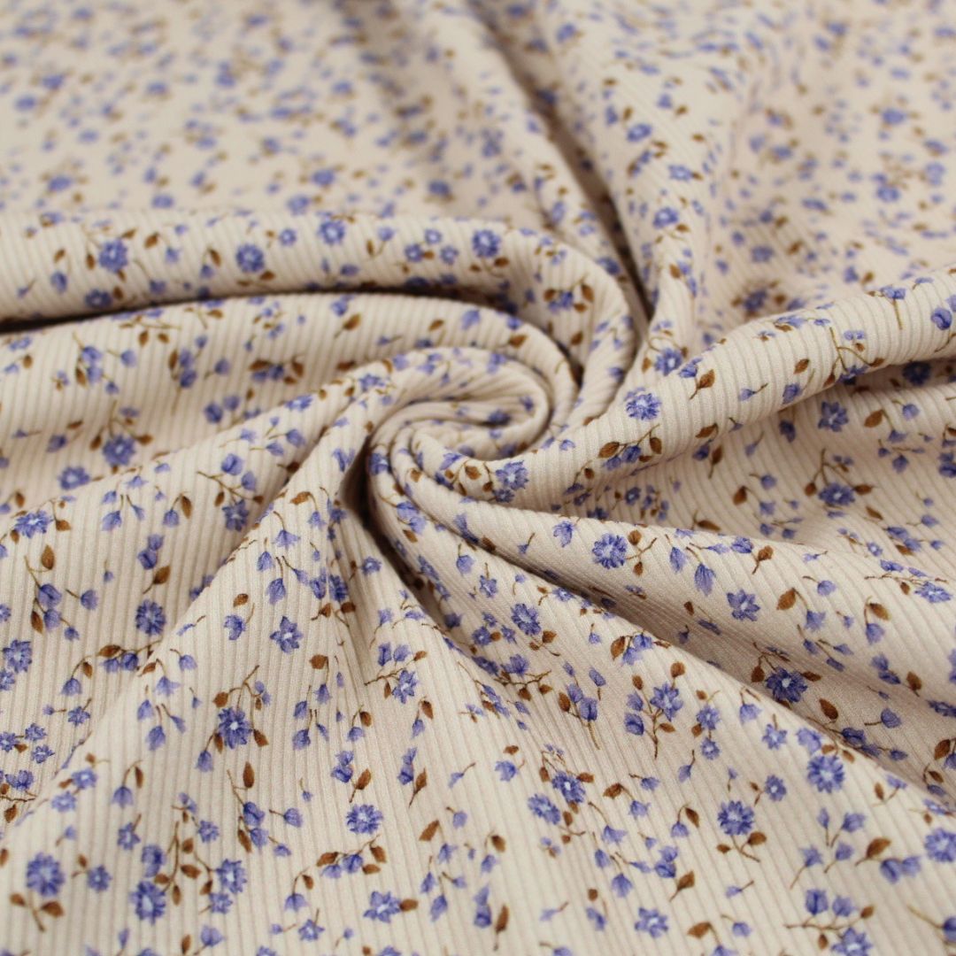 Gefalteter Rib Jersey Stoff mit kleinen blauen Blumen – zeigt die weiche und anschmiegsame Qualität des Materials.