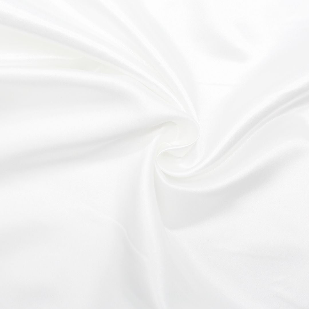 Nahaufnahme des glänzenden Satin-Stoffs in Ecru, ideal für Ballkleider und Dekorationen.