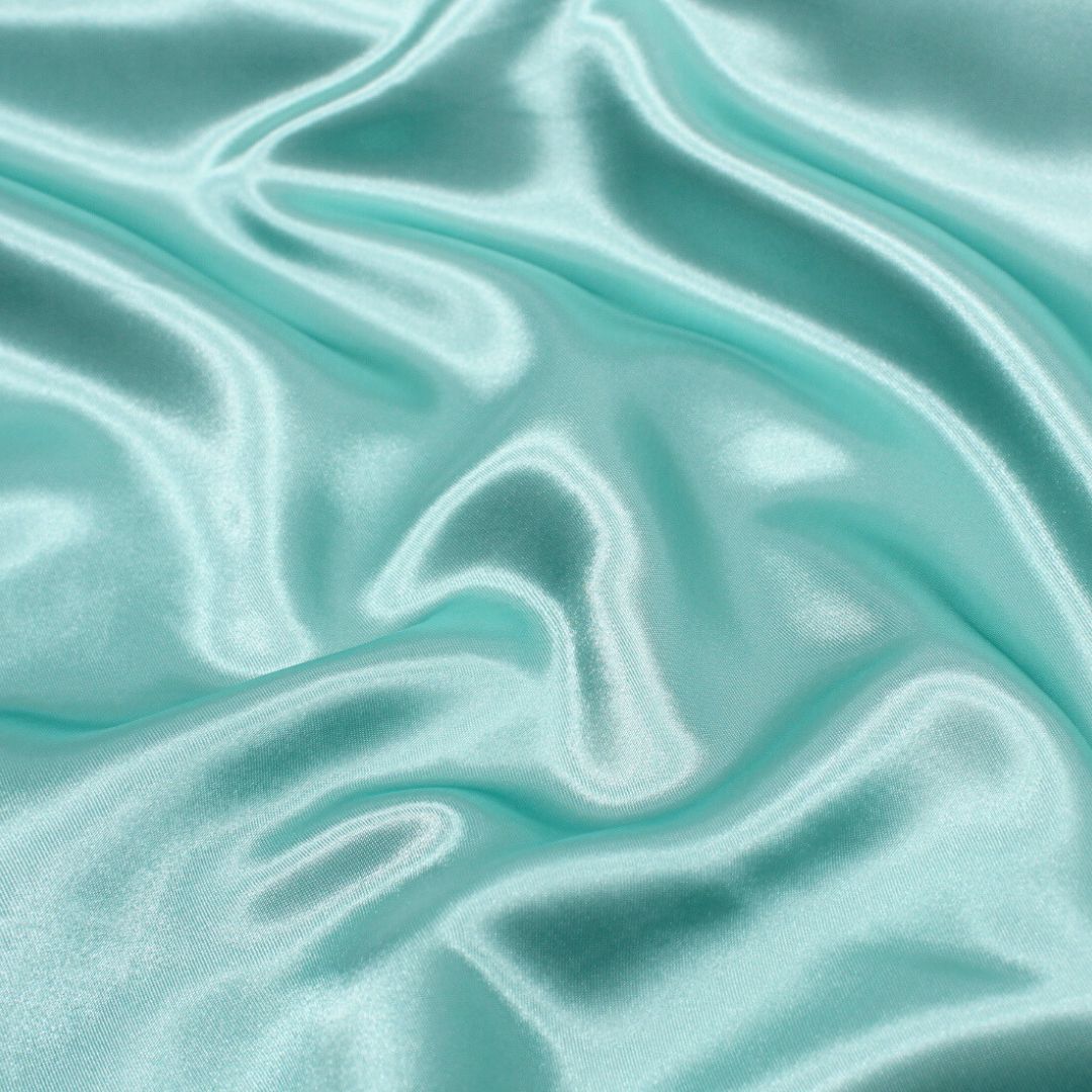 Nahaufnahme des glänzenden Satin-Stoffs in lebendiger Farbe, ideal für Ballkleider und Dekorationen.