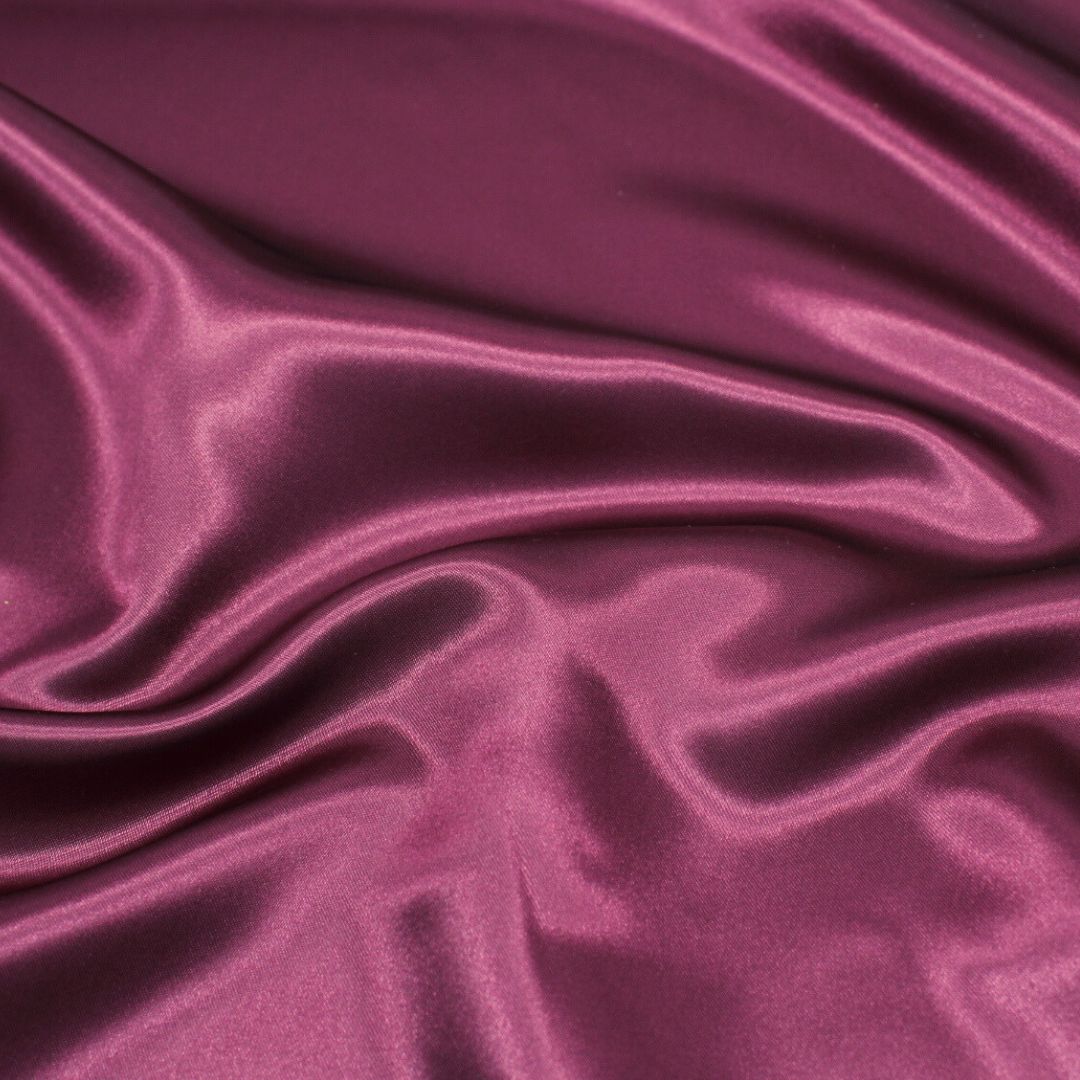 Nahaufnahme des glänzenden Satin-Stoffs in Weinrot, ideal für Ballkleider und Dekorationen.