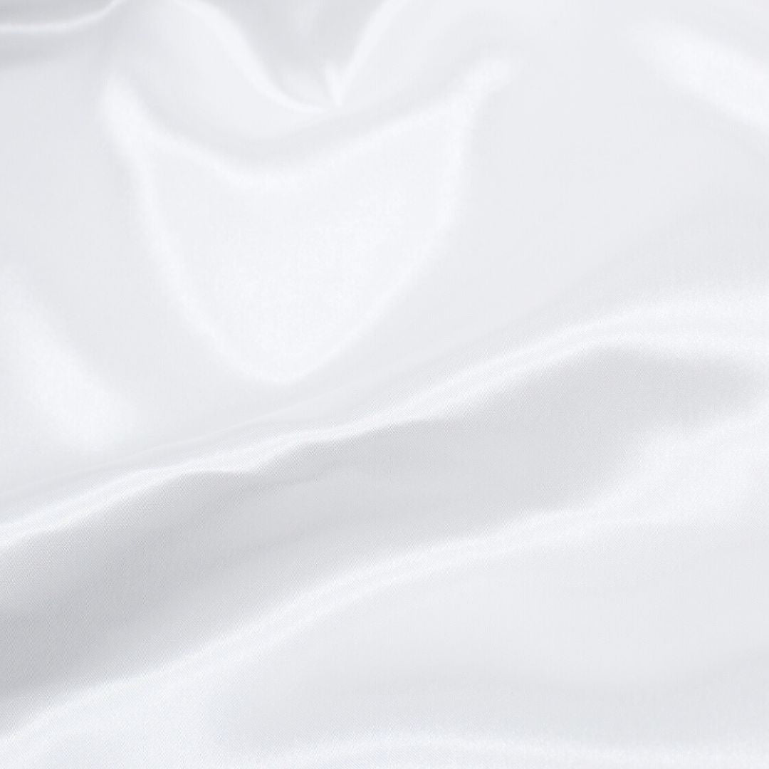 Nahaufnahme des glänzenden Satin-Stoffs in Weiß, ideal für Ballkleider und Dekorationen.
