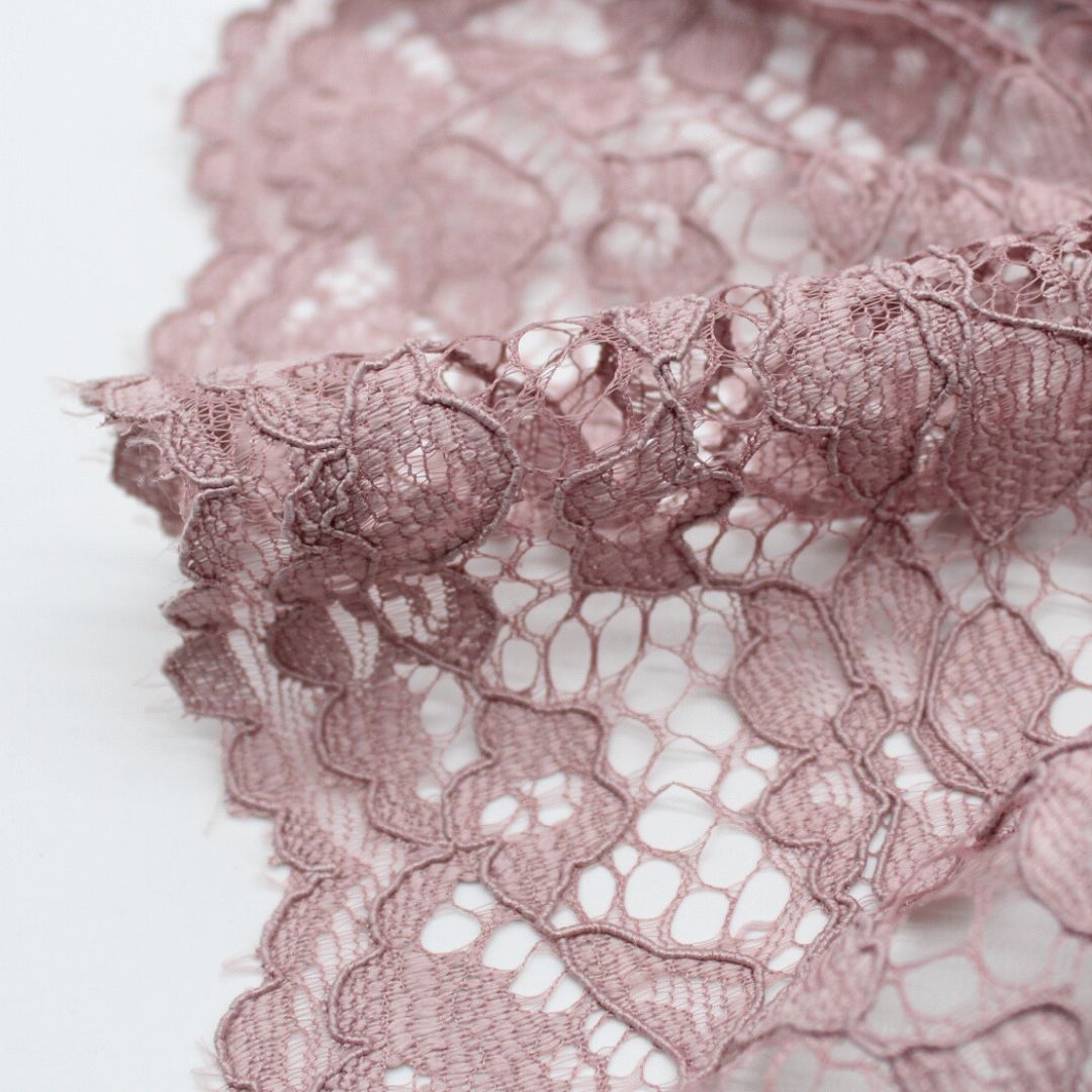 Nahaufnahme eines eleganten Spitzenstoffs mit filigranem Spitzensaum an beiden Seiten in Altrosa