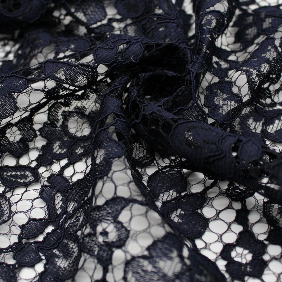 Nahaufnahme eines eleganten Spitzenstoffs mit filigranem Spitzensaum an beiden Seiten in Marineblau