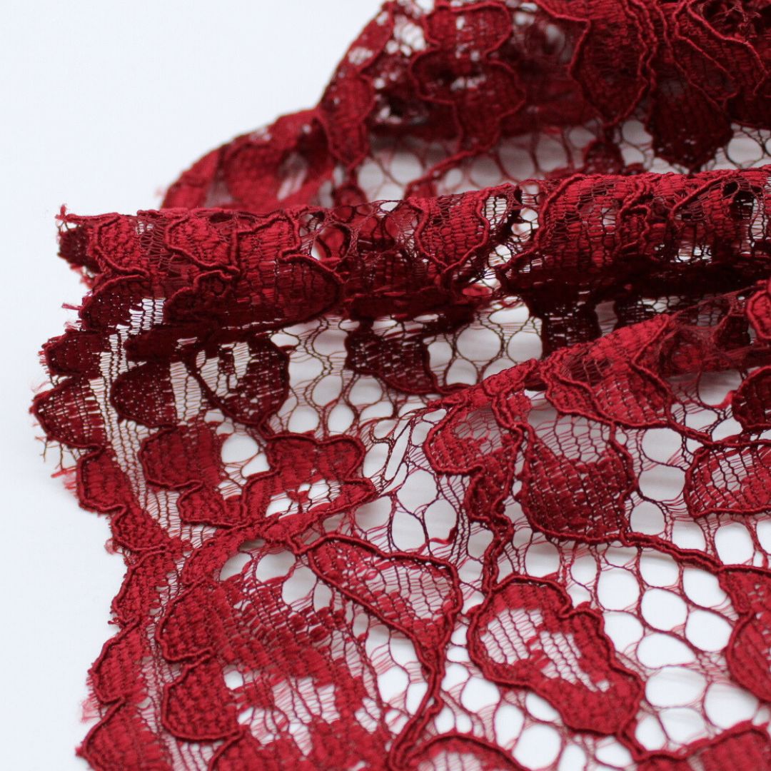 Nahaufnahme eines eleganten Spitzenstoffs mit filigranem Spitzensaum an beiden Seiten in Weinrot