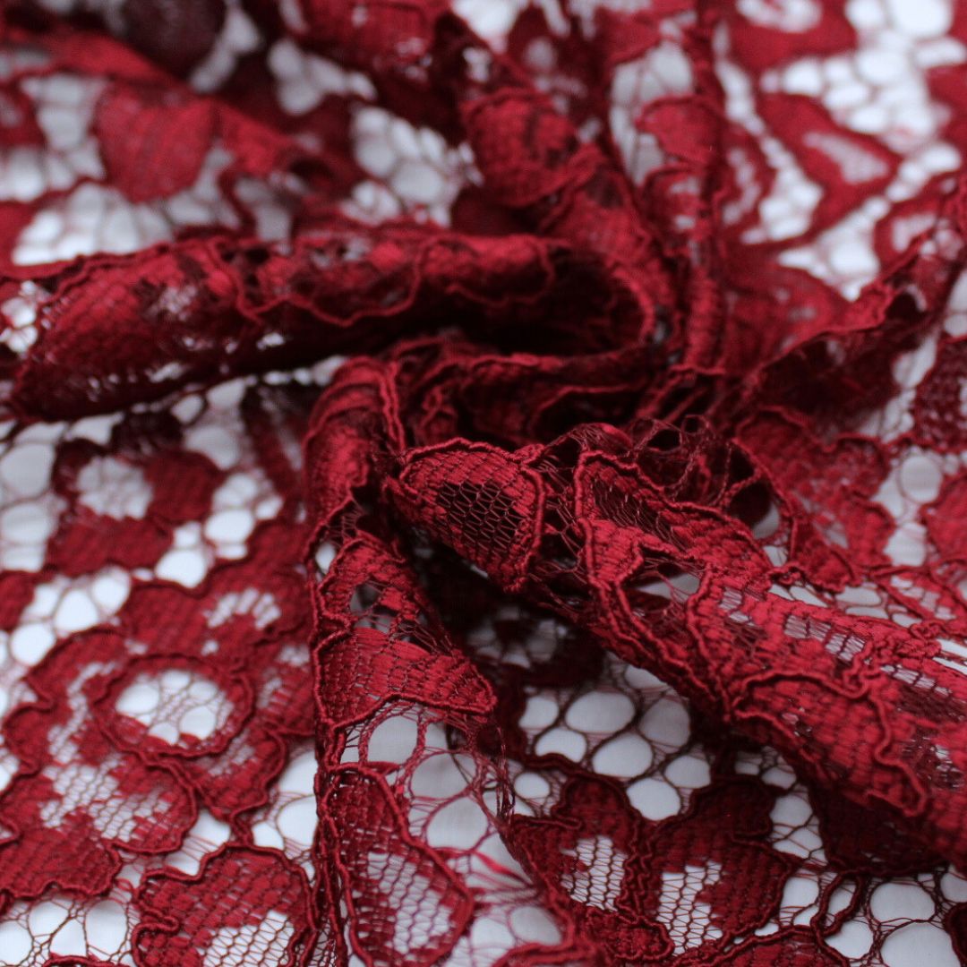 Nahaufnahme eines eleganten Spitzenstoffs mit filigranem Spitzensaum an beiden Seiten in Weinrot