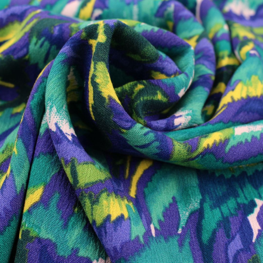 Beispiel für vernähten Crinkle-Stoff – Locker fallende Bluse aus Viskose Crinkle mit abstraktem Muster in Türkis, Gelb und Blau.