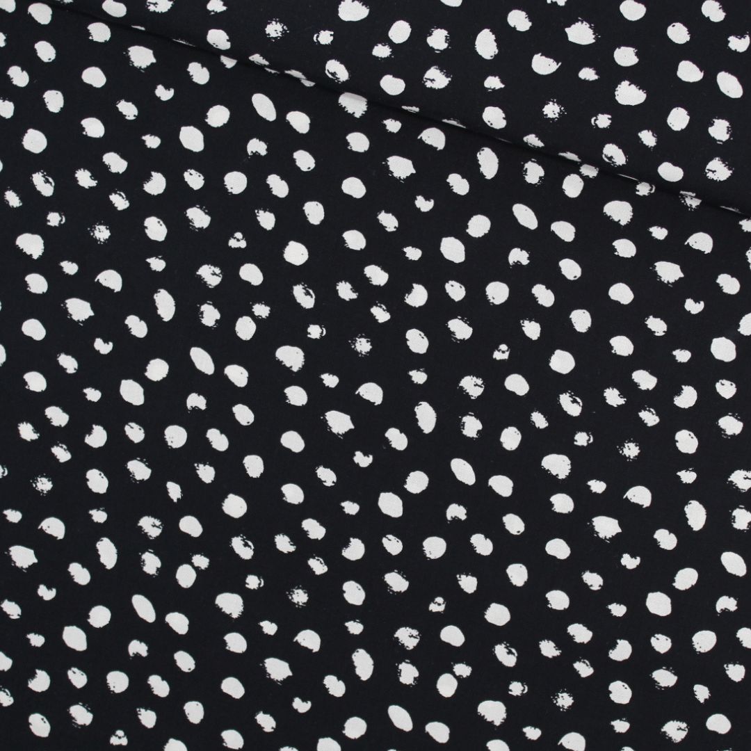 Viskosestoff mit kleinen unregelmäßigen Ecru-Punkten auf schwarzem Hintergrund, ideal für die Herstellung von Blusen, Kleidern und Röcken. Stoffball