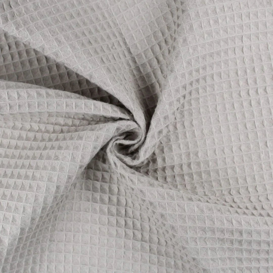Weicher Waffelpique-Stoff in natürlichem Taupe-Ton mit dreidimensionaler Wabenstruktur.