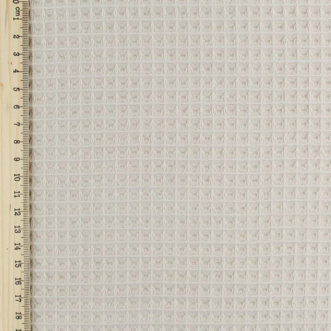 Fein gewebter Waffelstoff in zartem Beige-Ton, ideal für Heimtextilien und Bekleidung. Lineal