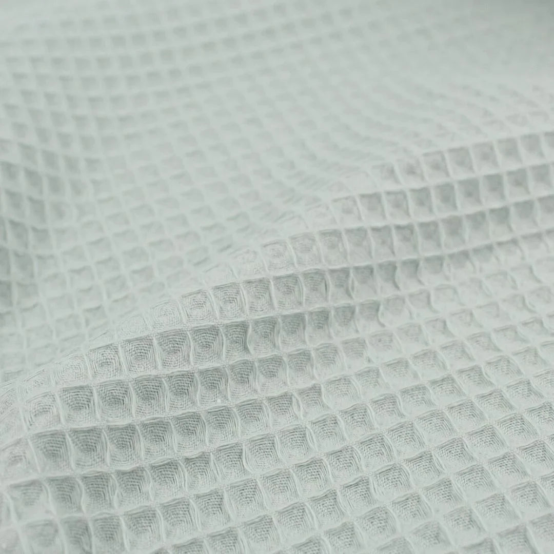 Detailansicht eines hochwertigen Waffelpique-Stoffs in Mintgrün mit dreidimensionaler Wabenstruktur.