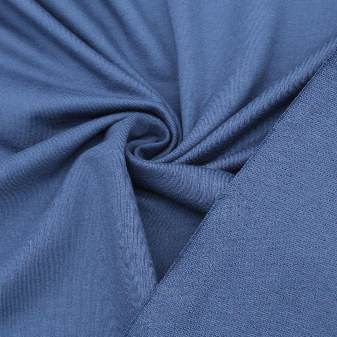 Nahaufnahme des French Terry Sweatstoffs in Jeansblau mit glatter Außenseite und typischer Schlingenstruktur auf der Innenseite.