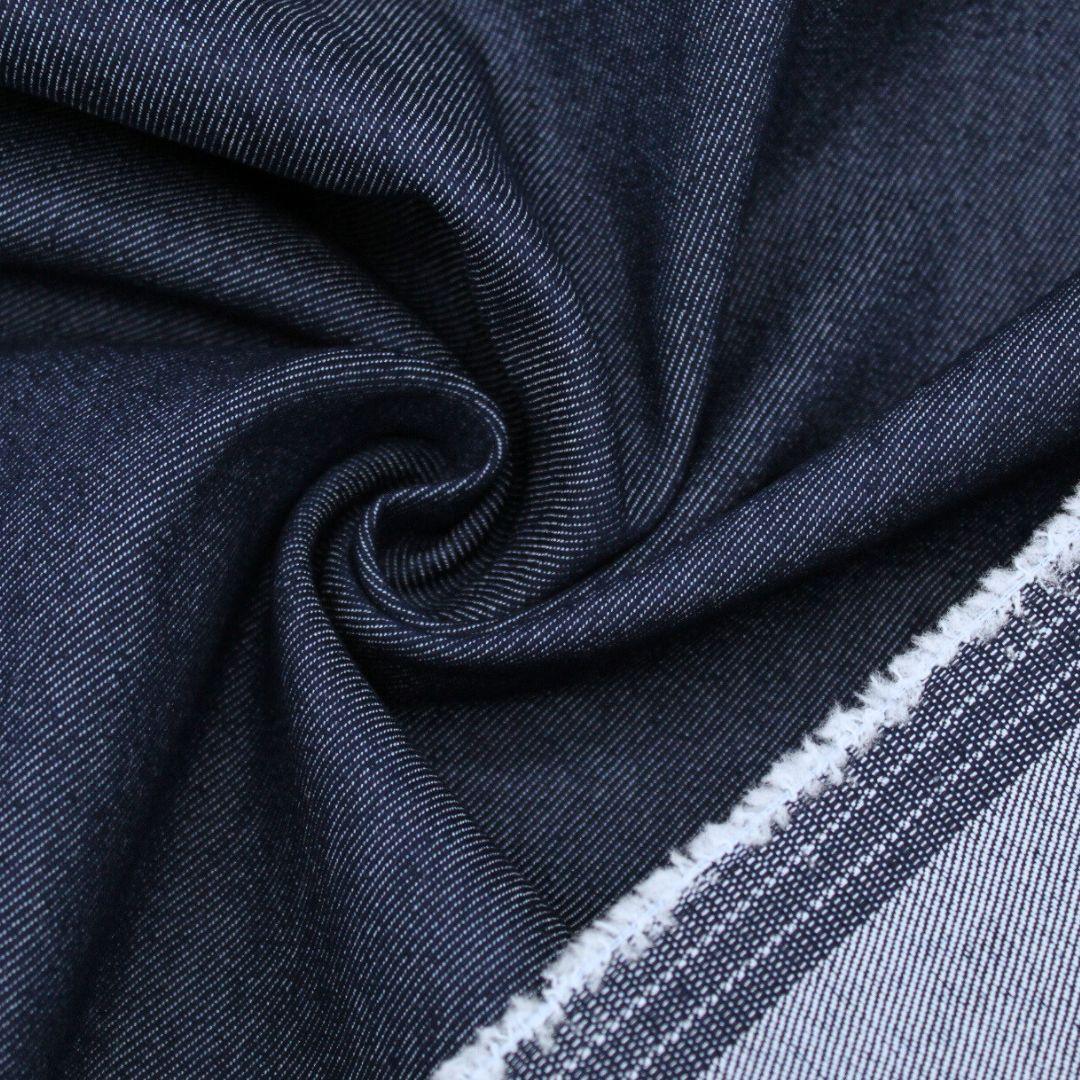 Nahaufnahme von robustem Jeansstoff, der die raue, körnige Oberfläche und die typische Textur zeigt. Indigo Blau mit Rückseite