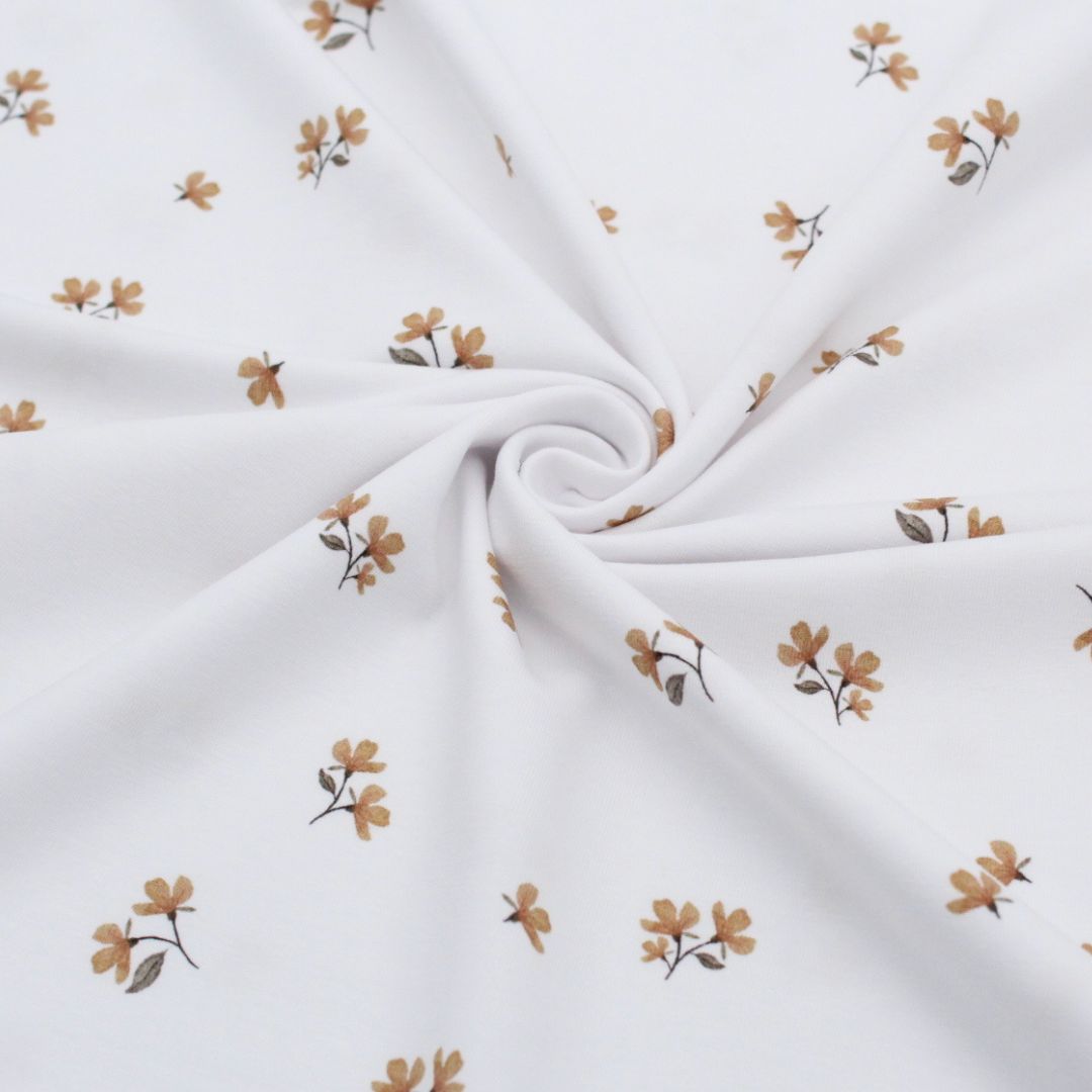 Jersey-Stoff mit floralen Blumen in Kamelbraun auf weißem Hintergrund. Detailaufnahme des eleganten Musters.