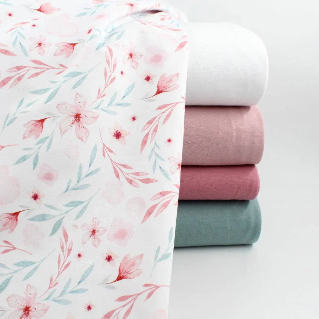 Hochwertiger Jersey mit floralen Motiven in Rosa-Blau auf Weiß – geeignet für Pumphosen, Mützen und Strampler