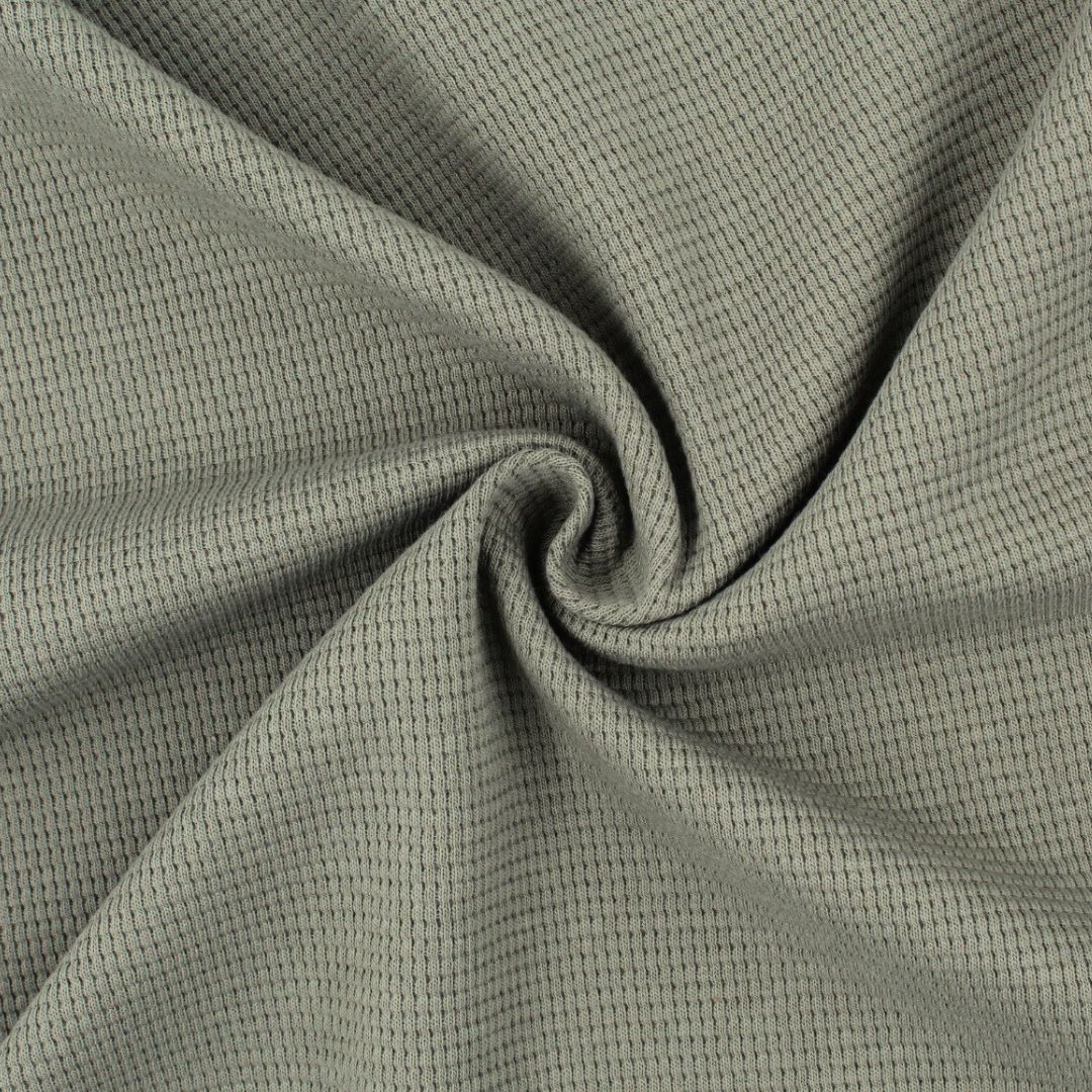 Detailaufnahme des Jersey-Stoffs, die die natürliche Baumwollfaser und den weichen Griff hervorhebt.