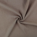 Weicher Musselinstoff (Double Gauze) in Taupe, locker drapiert, mit natürlicher Crinkle-Struktur und sanftem Fall.
