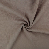 Weicher Musselinstoff (Double Gauze) in Taupe, locker drapiert, mit natürlicher Crinkle-Struktur und sanftem Fall.