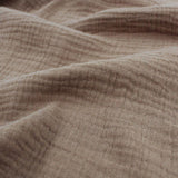  Mehrere Lagen Musselinstoff (Double Gauze) in Taupe übereinandergelegt, um die dezente Struktur und den sanften Farbton zu zeigen.