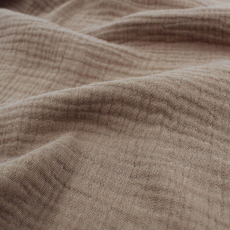  Mehrere Lagen Musselinstoff (Double Gauze) in Taupe übereinandergelegt, um die dezente Struktur und den sanften Farbton zu zeigen.