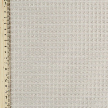 Fein gewebter Waffelstoff in zartem Beige-Ton, ideal für Heimtextilien und Bekleidung. Lineal