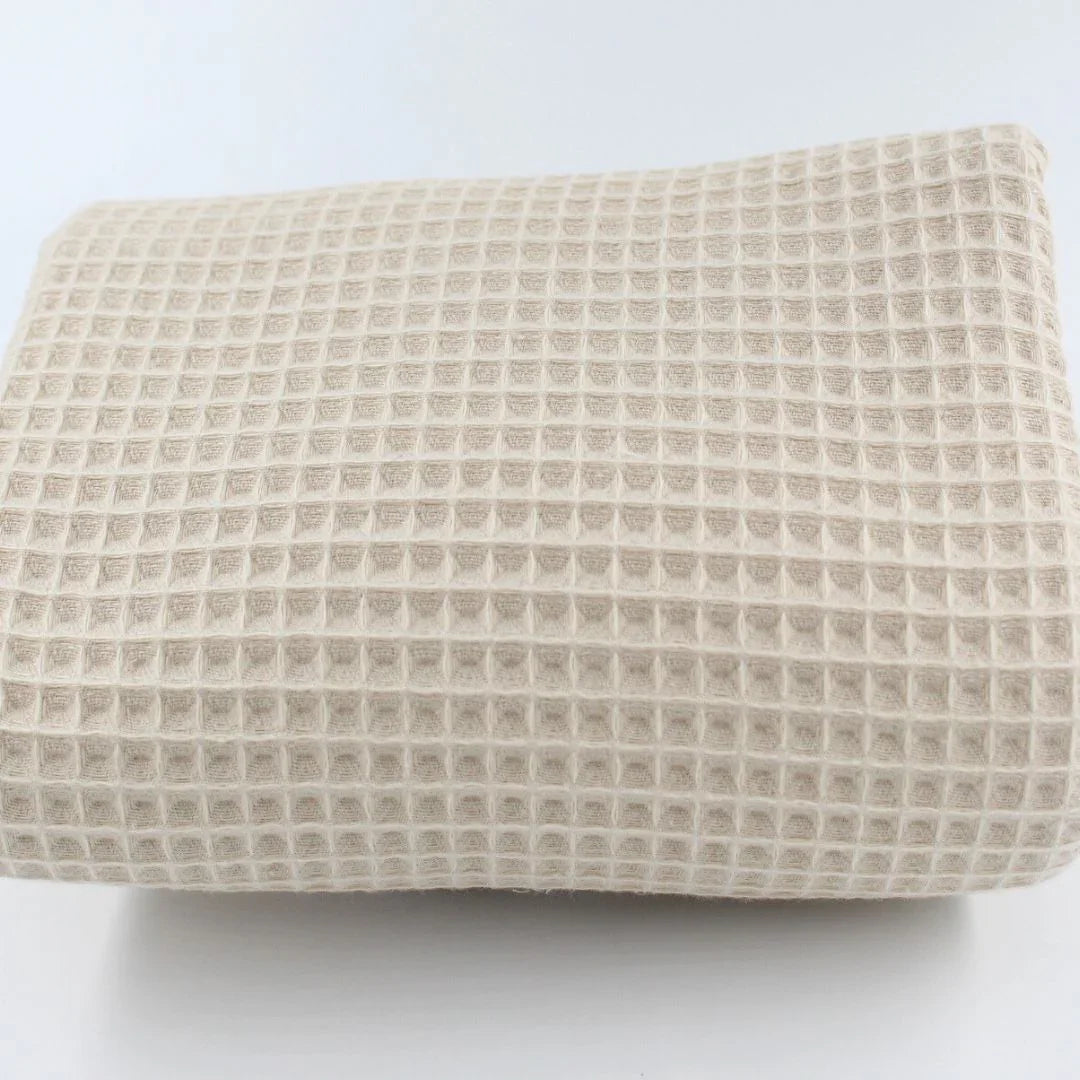 Detailansicht eines hochwertigen Waffelpique-Stoffs in Hellbeige mit dreidimensionaler Wabenstruktur.