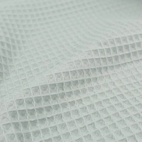 Detailansicht eines hochwertigen Waffelpique-Stoffs in Mintgrün mit dreidimensionaler Wabenstruktur.